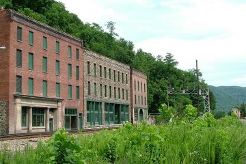 Abandoned buildings beside railway track and road