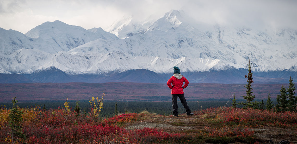 Woman standing facing mountain range.