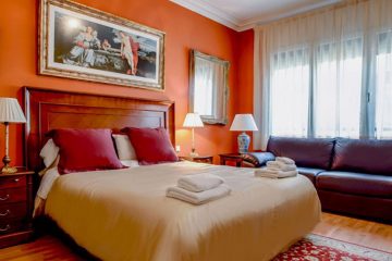 Hotel room with orange walls, leather couch and artwork