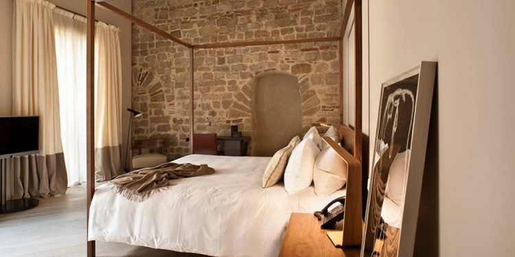 Four poster bed in room with stone wall