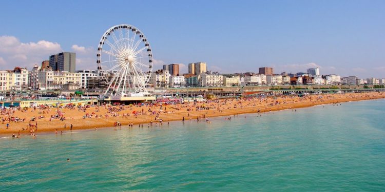 Beach with lots of people and Ferris wheel and buildings in background