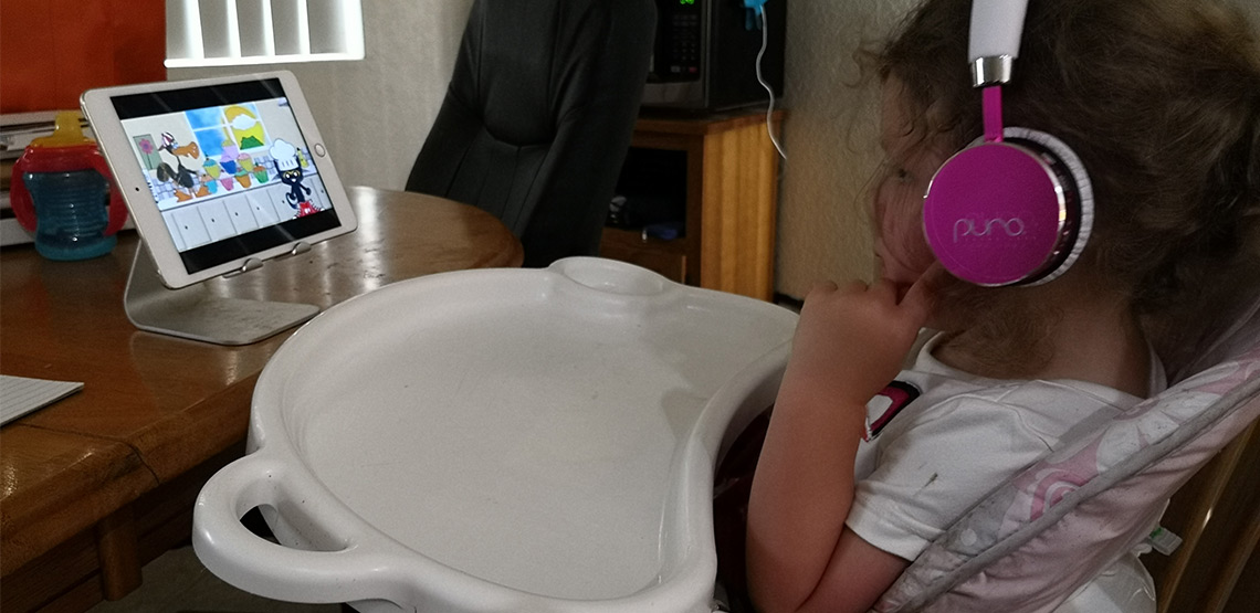 Little girl using headphones and watching show on iPad