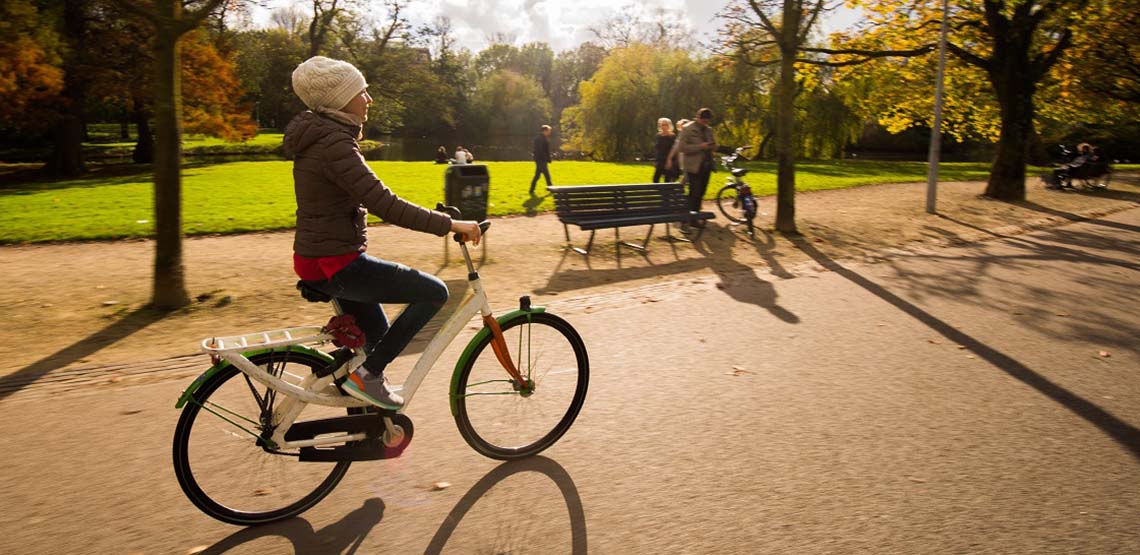 A Girl Rides a Bike in an Amsterdam Park.