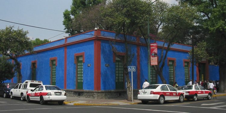 Blue house with cars parked along road