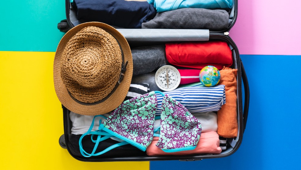 suitcase packed neatly with clothes, a hat and swimsuit on top