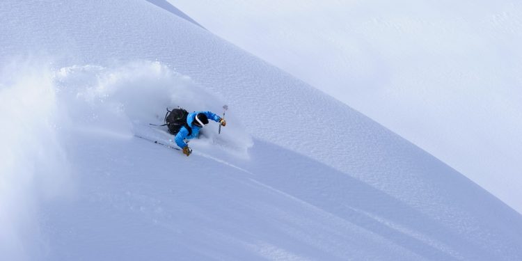 A skier shreds powder from an umarked slope.