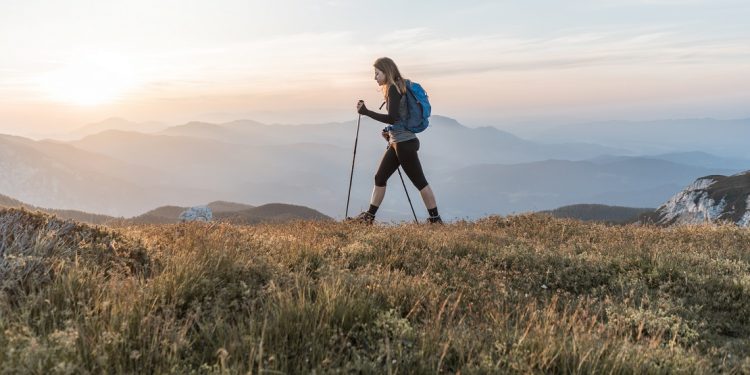 A woman strides across a grass-covered ridge in Slovenia.