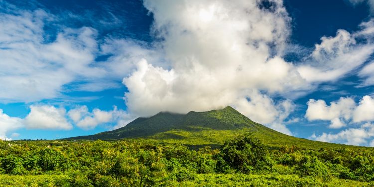 A cloudy cap rests on a green tropical mountain peak.