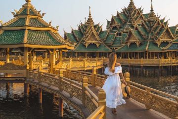 A lady in a white dress walking on a brown bridge.