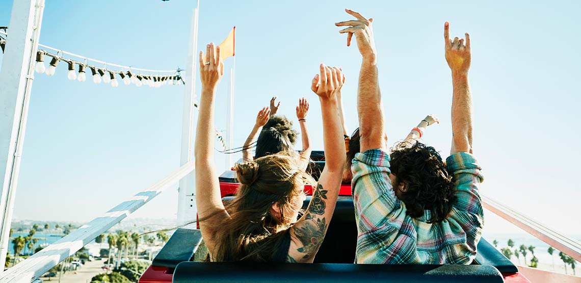 People riding on a rollercoaster with their arms up.