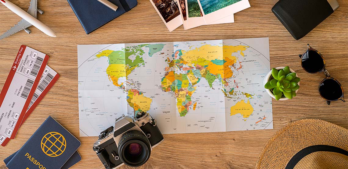 A travel flatlay with a travel map, camera, sunglasses and a passport.