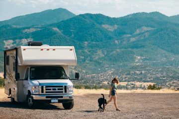 A women getting out of a white RV with her dog.