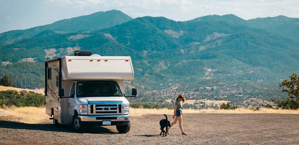 A women getting out of a white RV with her dog.