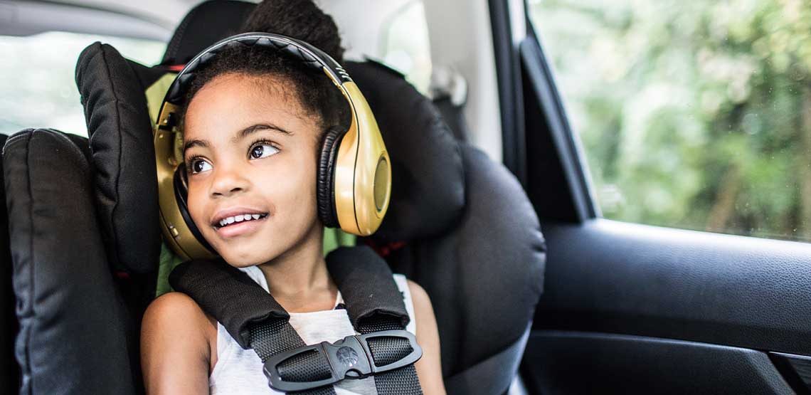 A child in a car seat wearing headphones.