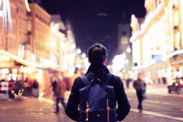 A person walking in Europe at night with Christmas lights.